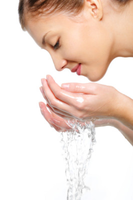 female washing her face with water